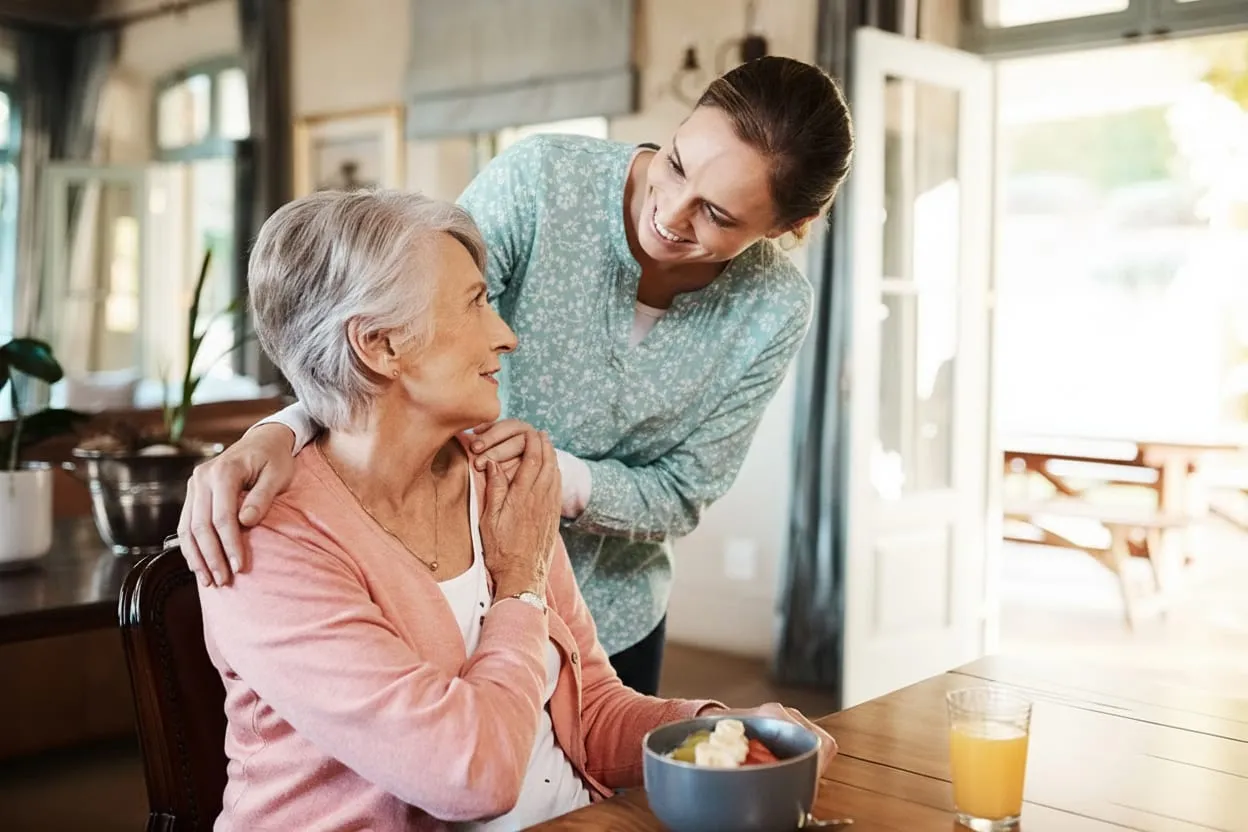 A caregiver and an older woman sharing a laugh at home